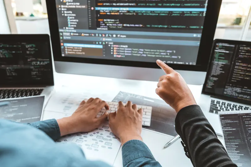Programadores revisando código em um monitor